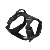Black dog harness with one side of a black magnetic buckle, an orange vegan leather handle, and two aluminum rings, one on the back, and the other on the front, on a white background  