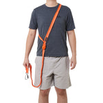 Person wearing a gray t-shirt and beige shorts with a crossbody orange dog leash over their shoulder on a white background