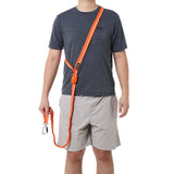 Person wearing a gray t-shirt and beige shorts with a crossbody orange dog leash over their shoulder on a white background