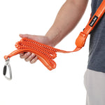 Person holding an orange dog leash with a carabiner on a white background