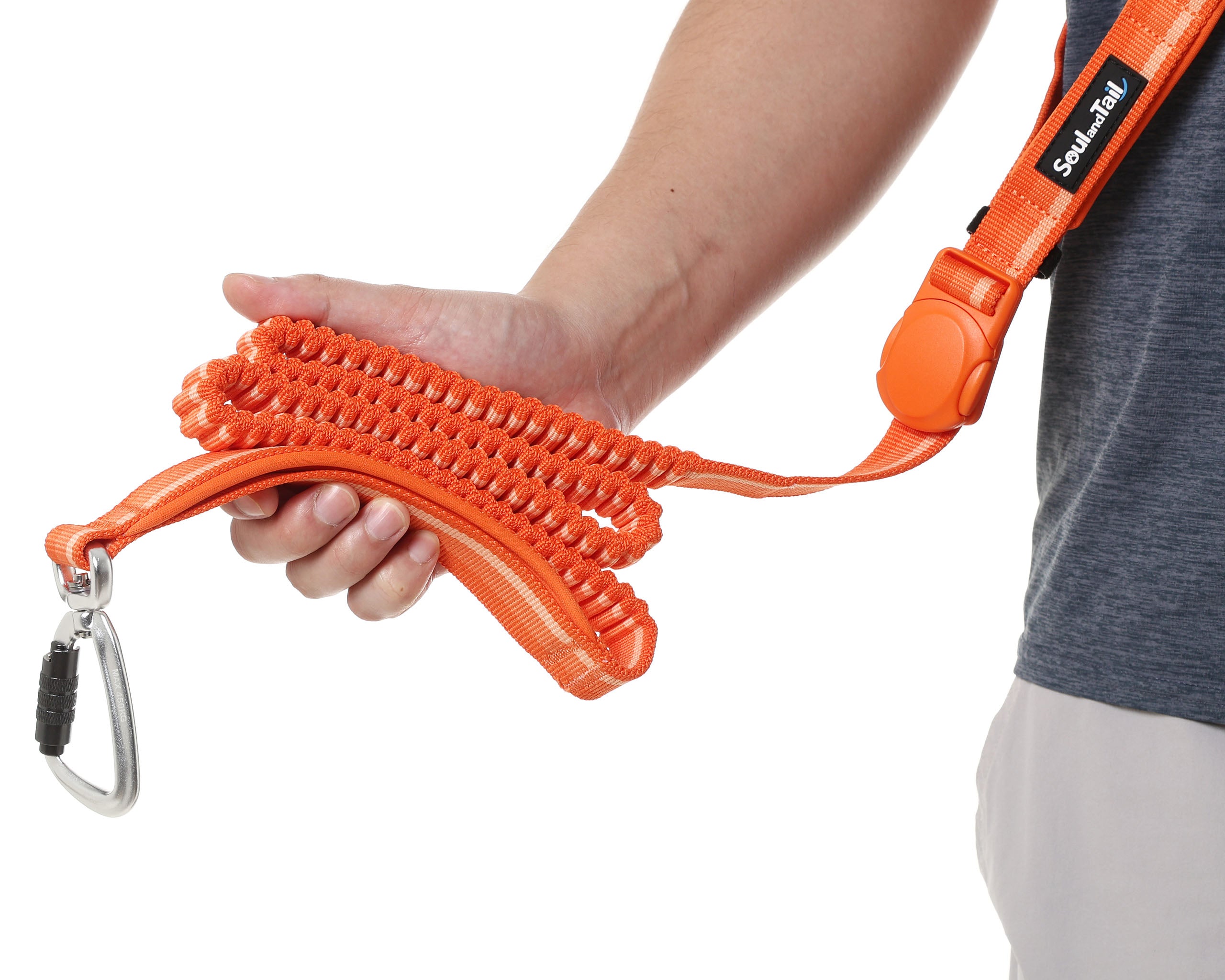 Person holding an orange dog leash with a carabiner on a white background