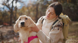 Woman with a backpack petting a dog in a forest