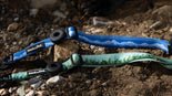Two dog collars with nature-themed designs on a rocky ground.
