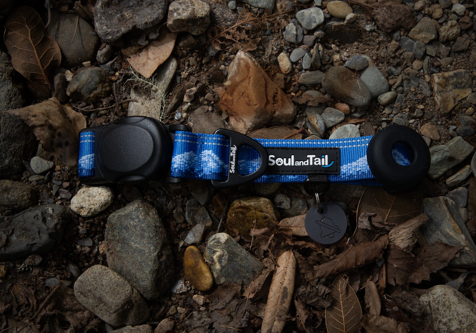 A blue dog collar with black magnetic buckle on a rocky ground